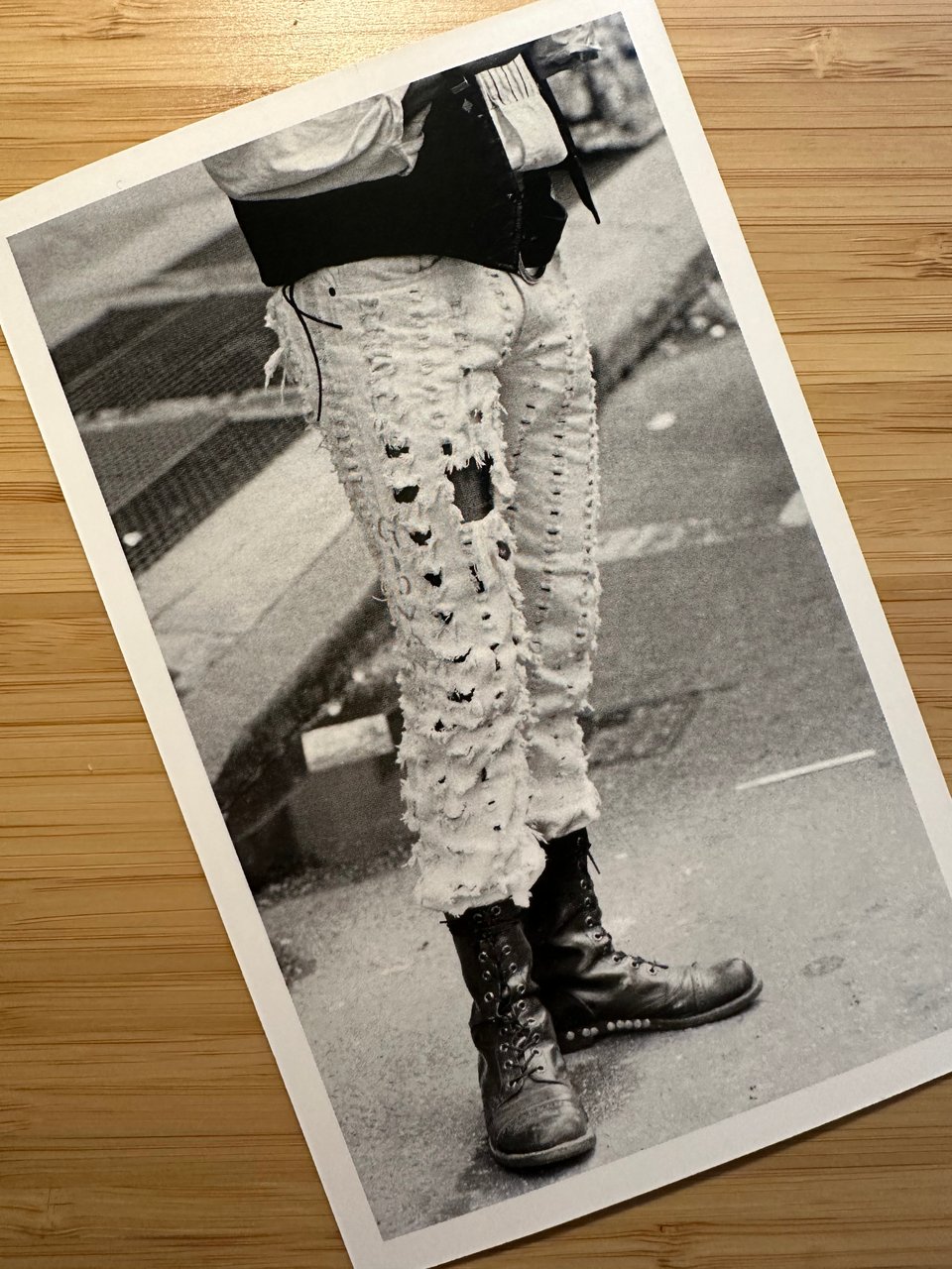 photo of a postcard of a b/w pic of a person in carefully shredded jeans and combat boots