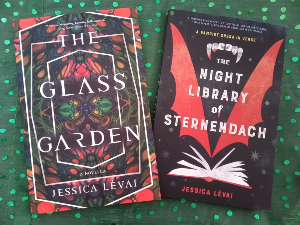 THE GLASS GARDEN, with its kaleidoscopic cover, and THE NIGHT LIBRARY OF STERNENDACH, with its batwing and book cover, rest on a festive sparkly green background.