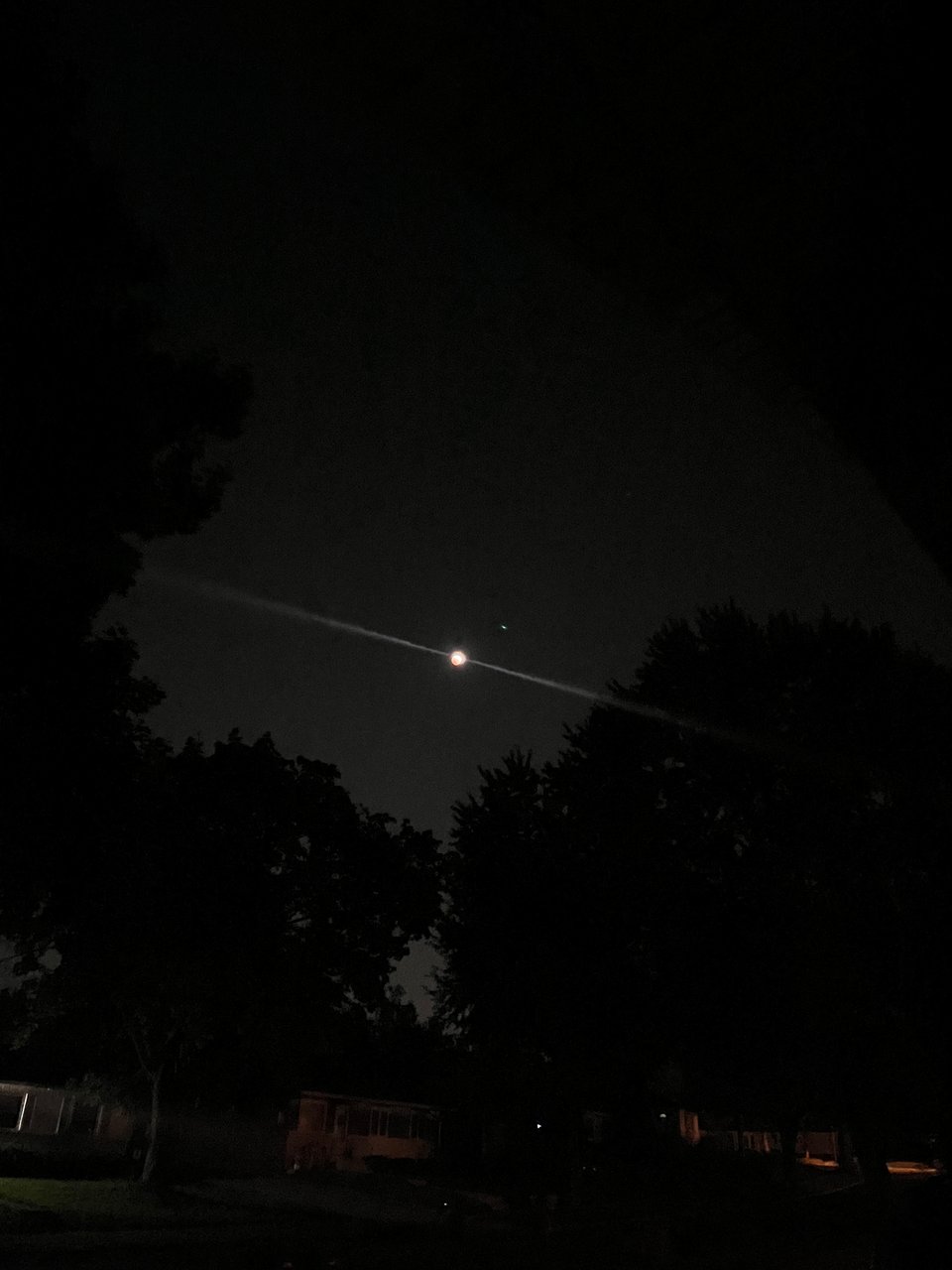 dark sky with a small, bright, clear moon and black tree silhouettes