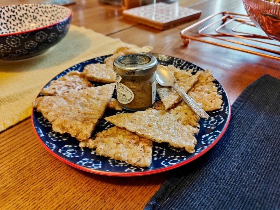 A plate of pearl barley pancake cut up with a small jar of mustard in the centre.