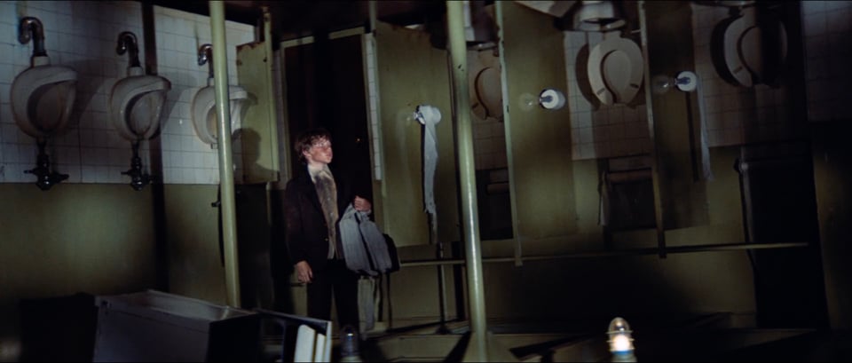 A young boy is inside a large restroom, but everything including the toilets is upside down.