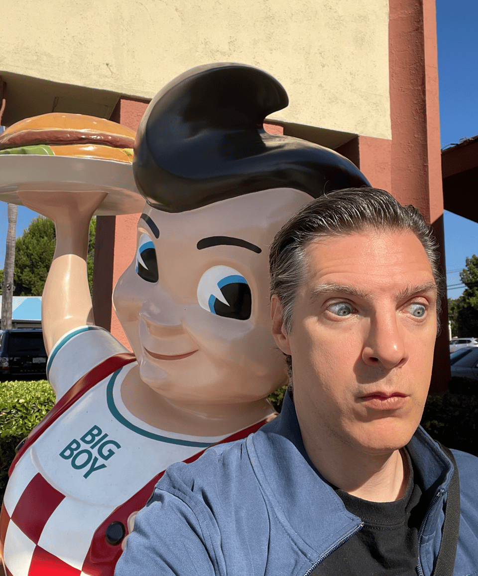 A statue of a big boy with a hamburger leans into a man with a shocked look on his face