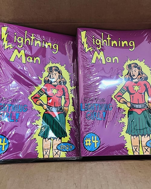 Copies of Lightning Man #4 in a cardboard box.