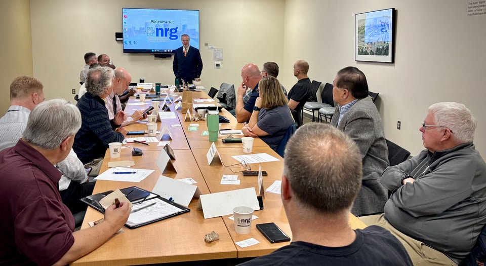 Darryl stands at the front of the room while talking to seated NRG members.