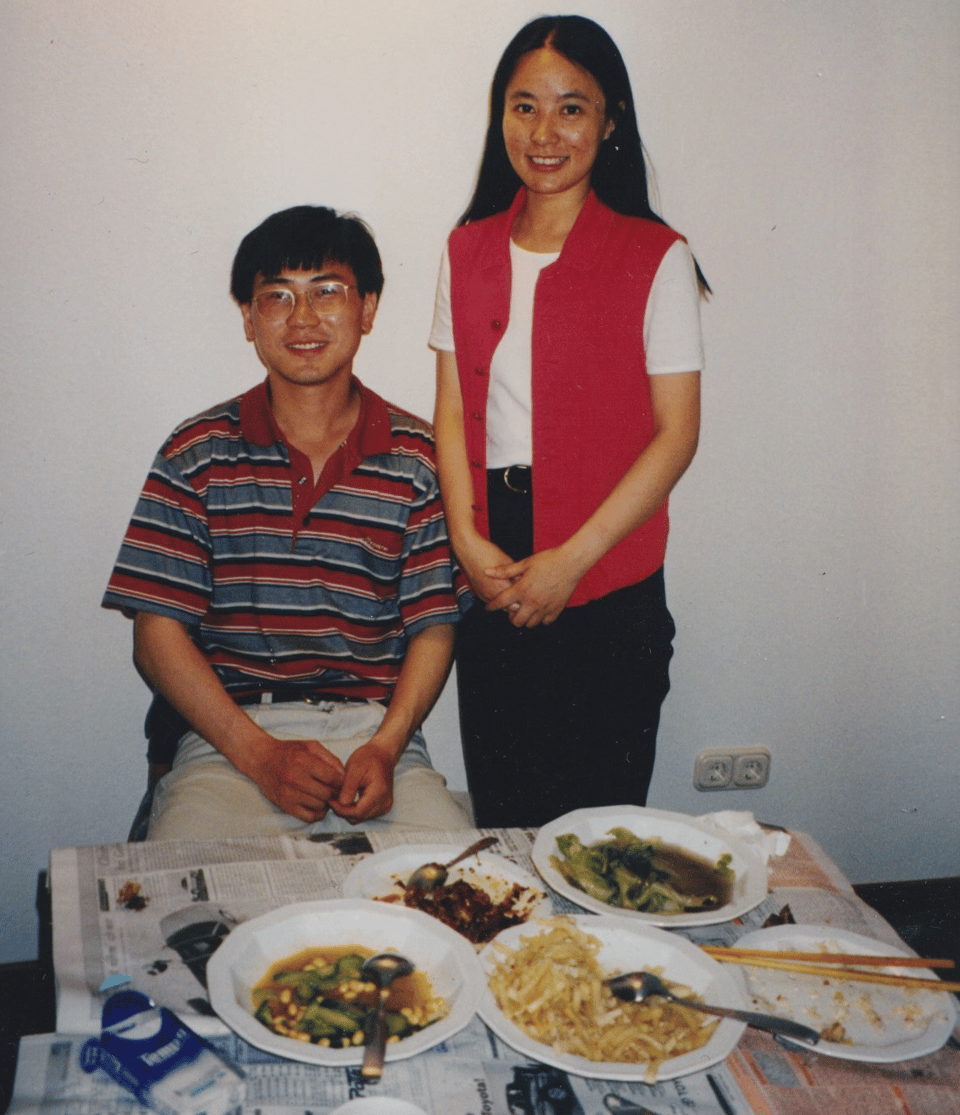 A young Chinese man and woman standing by a table with plates of food