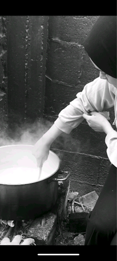 Image of a woman stirring a pot, in black and white.