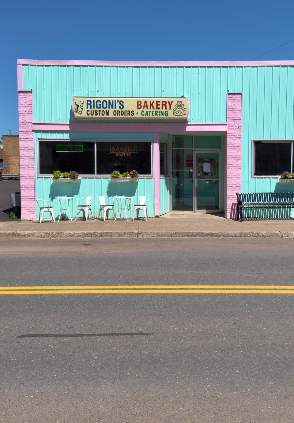 Photograph of a bakery with chairs and table in front