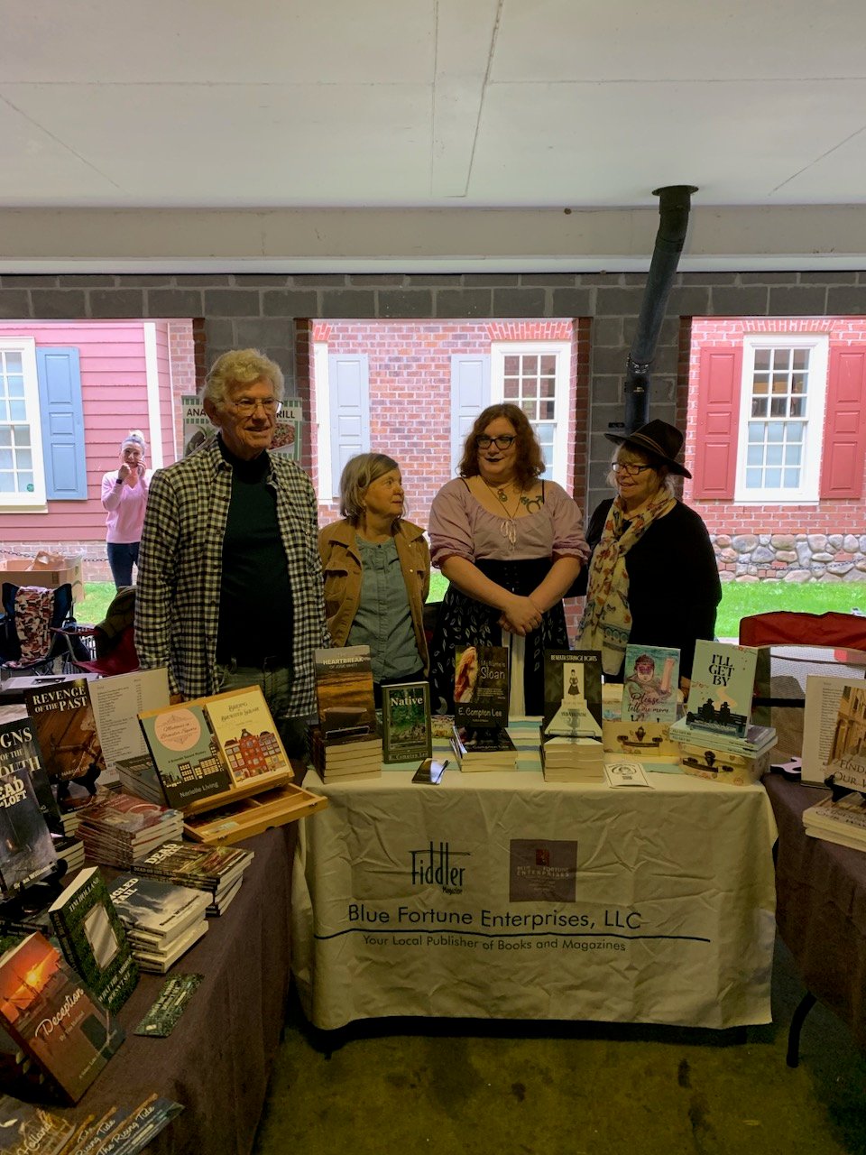 Vivian Moira Valentine and three other writers standing behind the Blue Fortune Enterprises display table