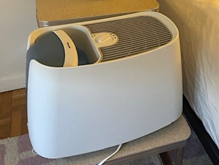 A white humidifier on a bedside table