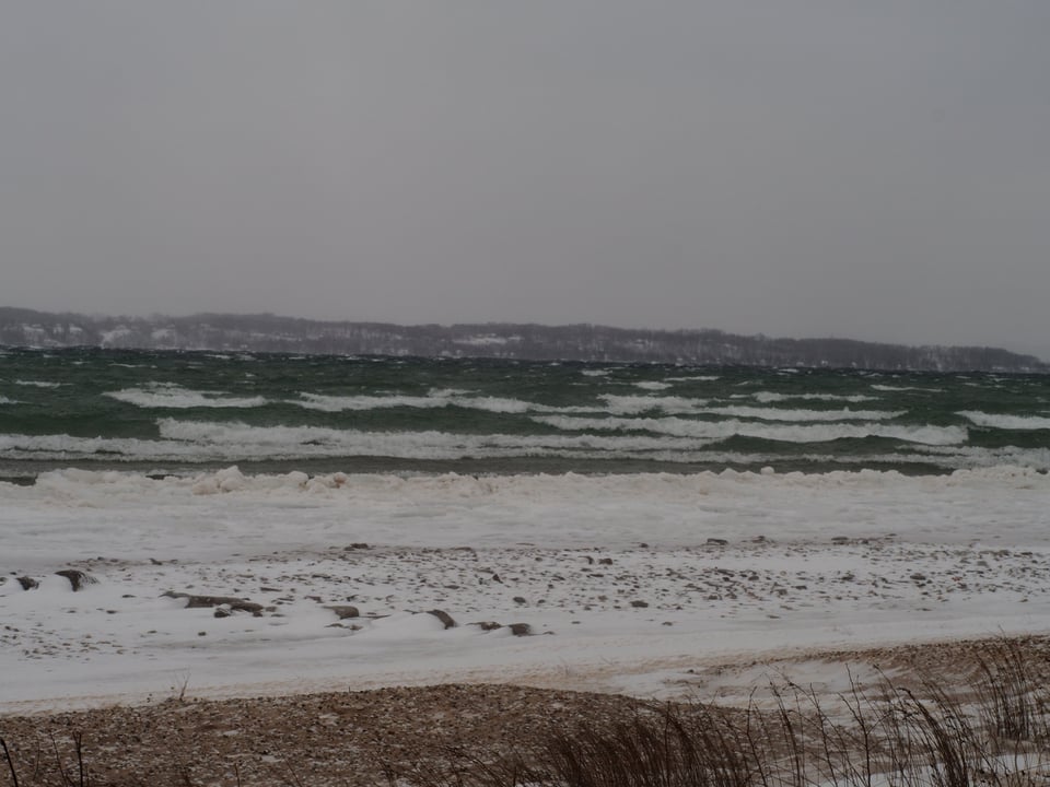 A cold Lake Michigan, with white caps, snow, and sand