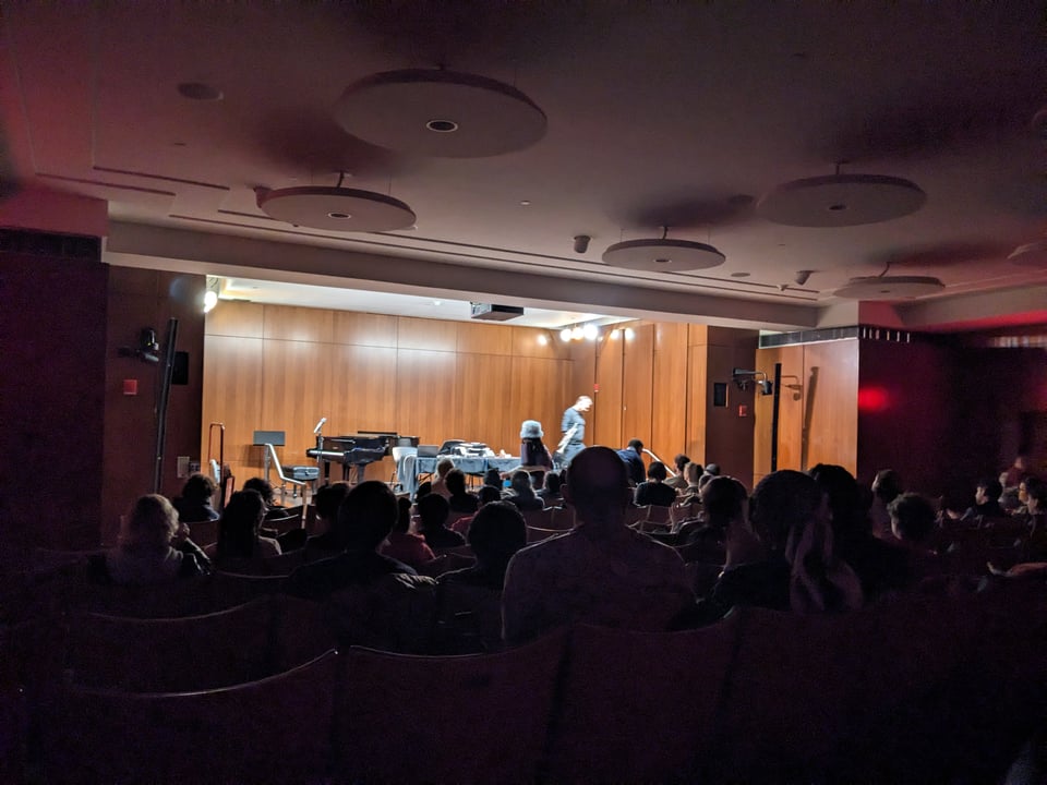 a darkened room with a stage in front where a musician is blurrily crossing the stage.