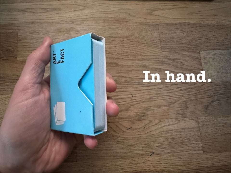A hand holding some Artefact Cards in their box