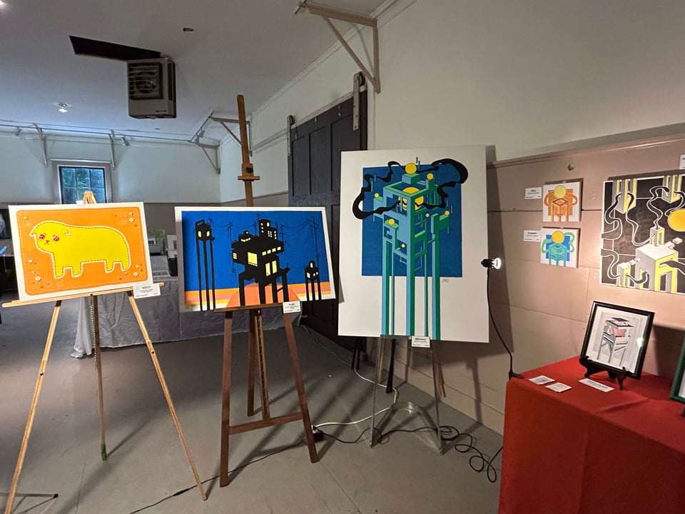 Large paintings displayed on easels in a studio room. They depict whimsical and fantastical imagery.