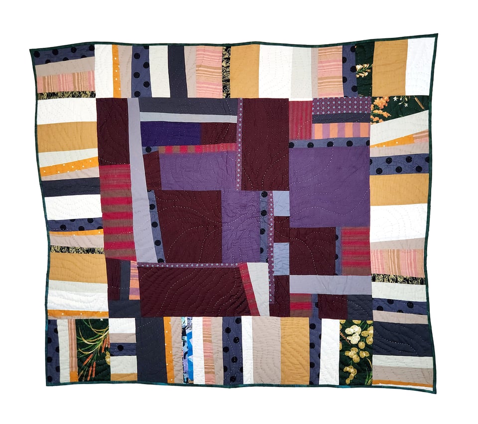 Photo of Concrete Path, a patchwork quilt by Sarah Atlee. The middle section of this square quilt has rectangles of fabric in many shades of purple. The outer border has strips of fabric in white, tan, and dark green.