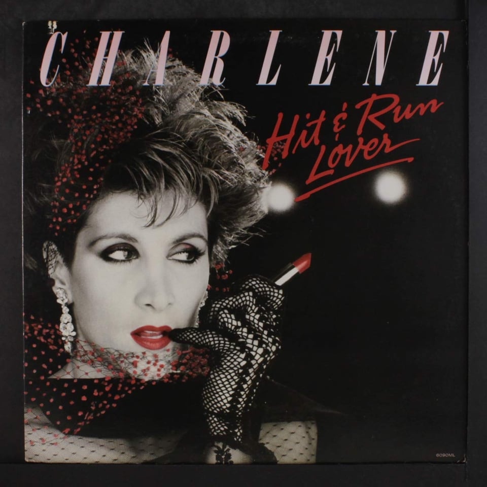 The cover of Hit and Run Lover by Charlene, featuring a white woman with new wave hair wearing a lacy  glove and applying bright red lipstick