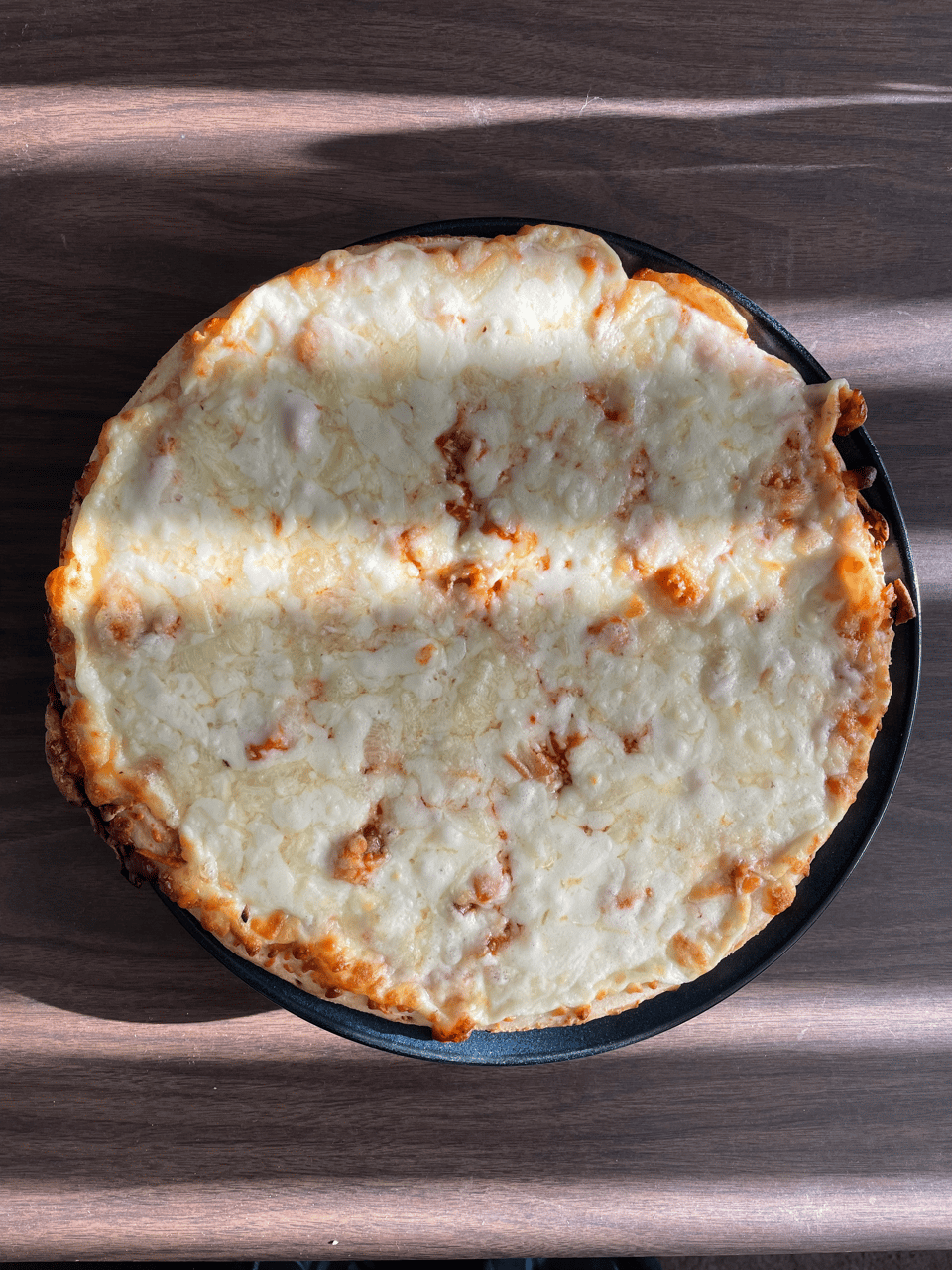A cheese pizza covered in shadows and the last glow of twilight