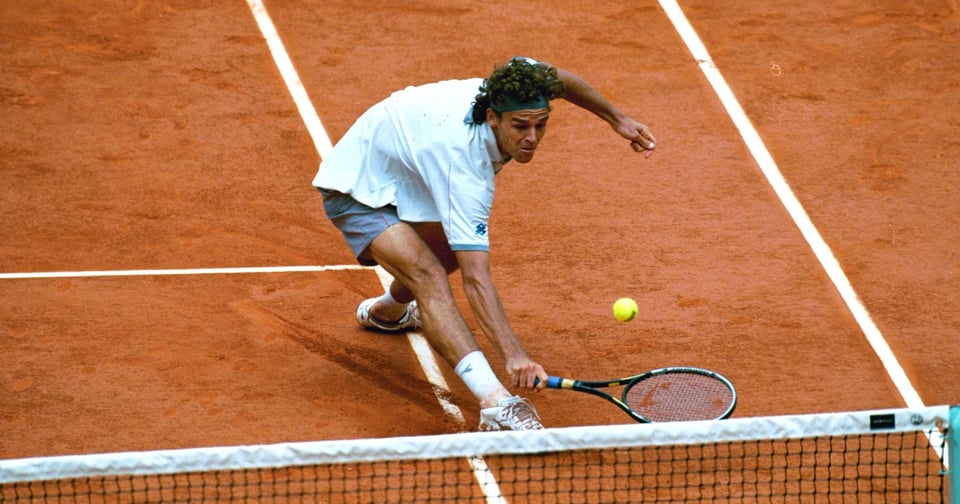 Imagem do tênis Gustavo Kuerten jogando em uma quadra de saibro