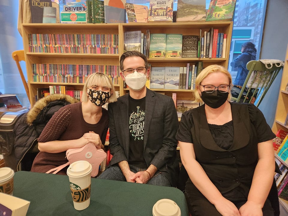 Sienna Tristen, Brandon Crilly and Kate Heartfield. We are wearing masks and have a bookshelf behind us.