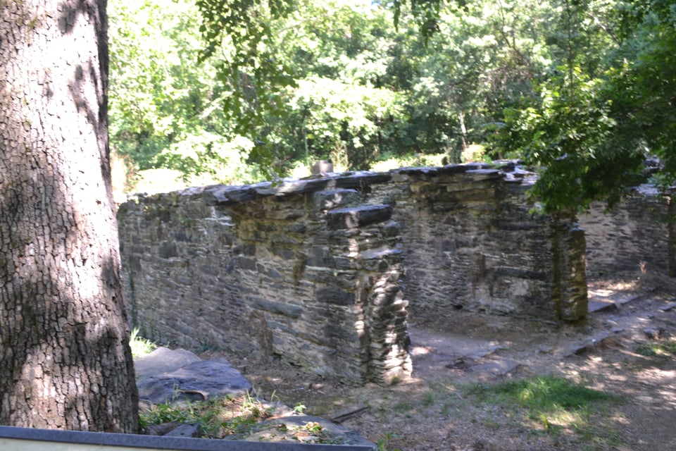 Three evenly spaced stone walls, about six feet high, surrounded by trees.