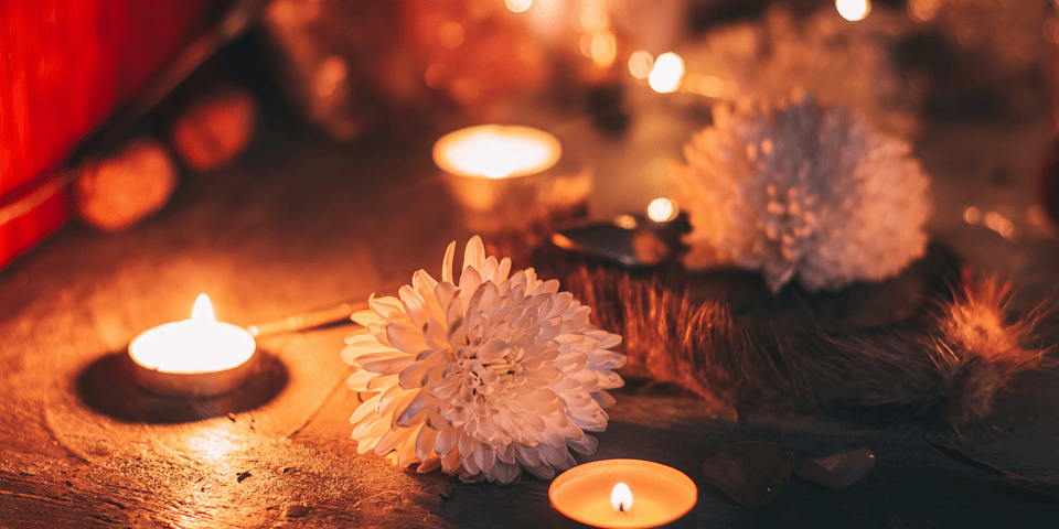 A wooden altar contains a circle of tea lights and several pink flowers in an arrangement. Witchcraft is happening!