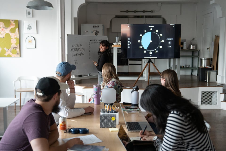 A table of people looking at Livvy writing on a whiteboard.