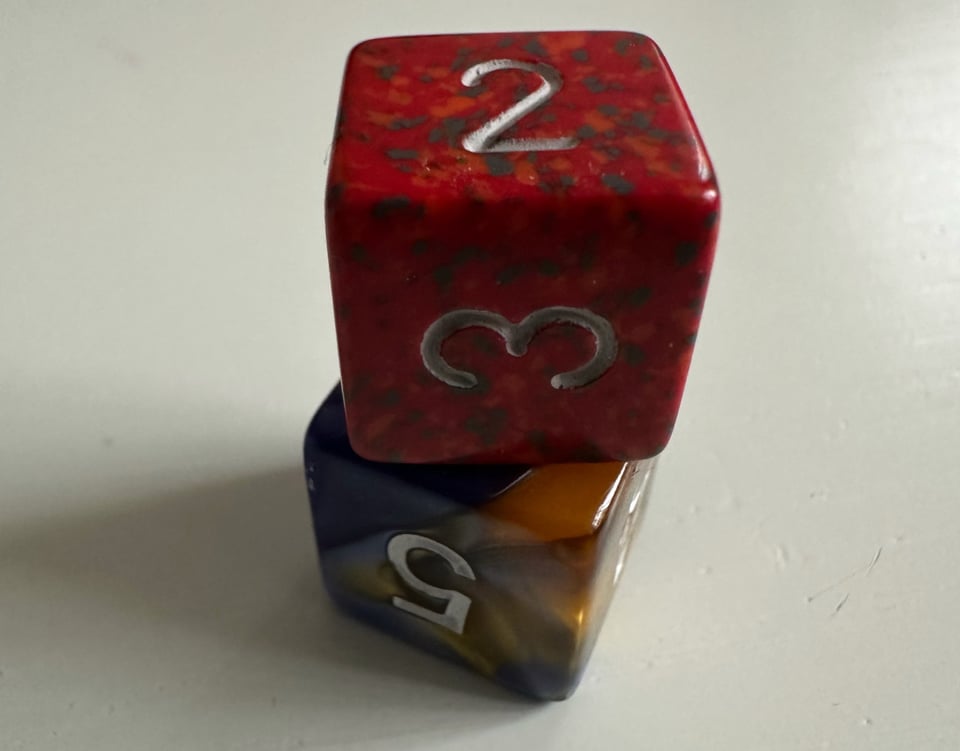 Two six sided dice. One is balanced on top of the other.