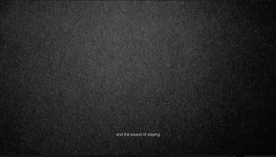 Grainy black image with centered white subtitle: “and the sound of staying”