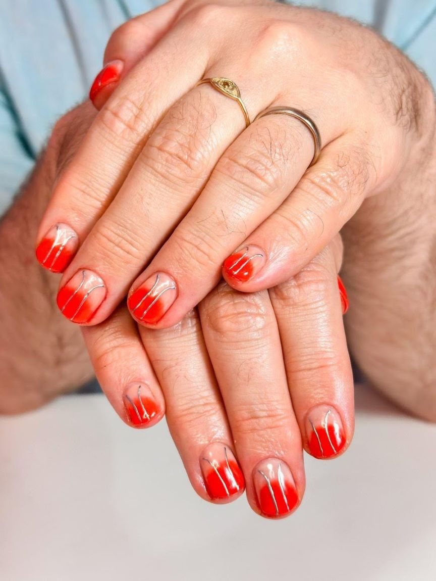 A red ombré manicure with lines of silver through it.
