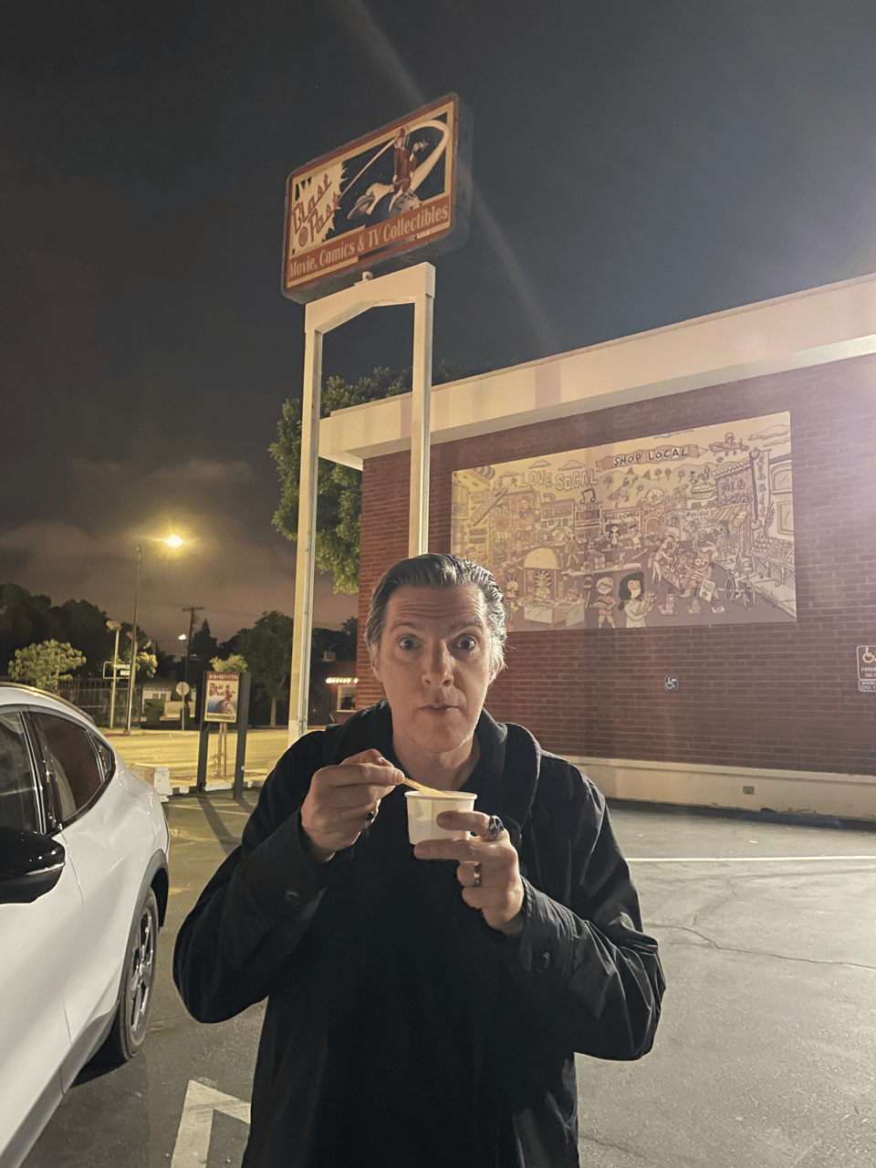 A man eats gelato at night in front of a toy store called Blast From The Past