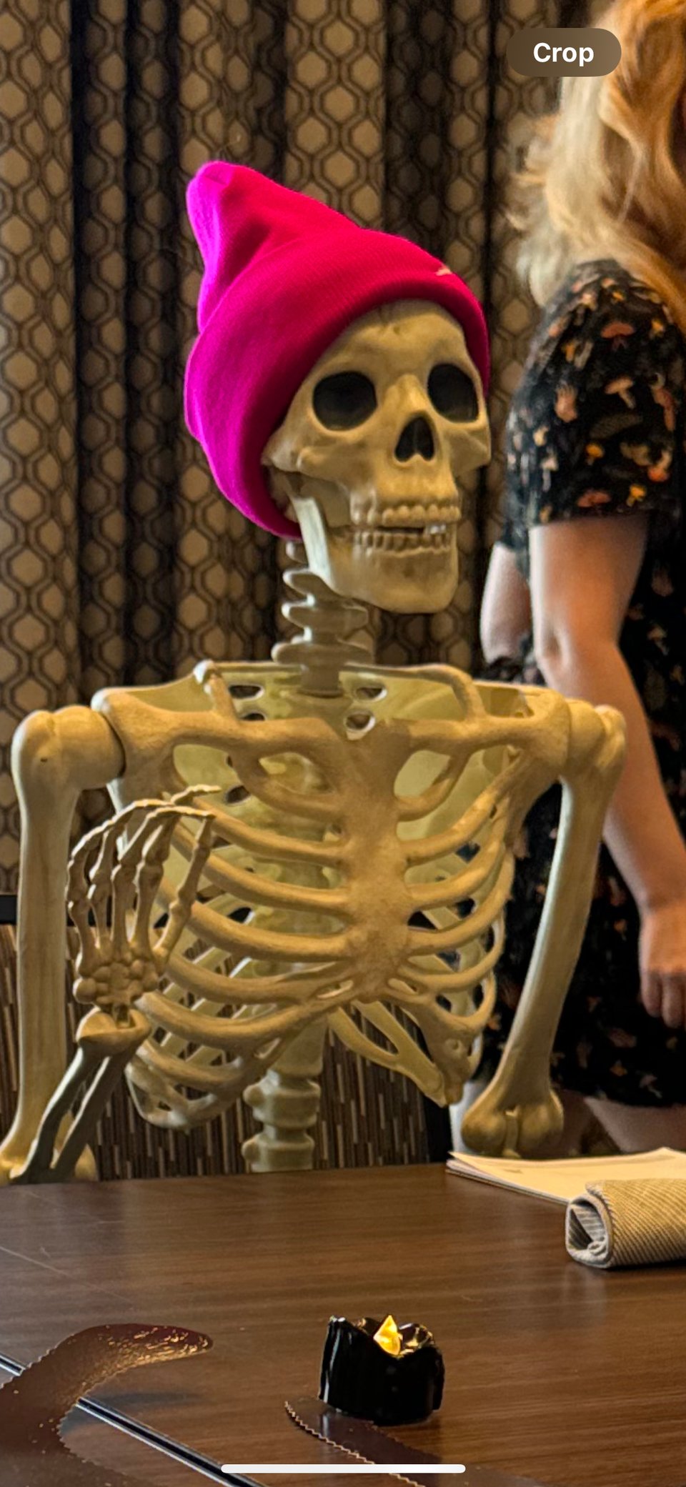 Skeleton raising his hand politely to speak at a conference table
