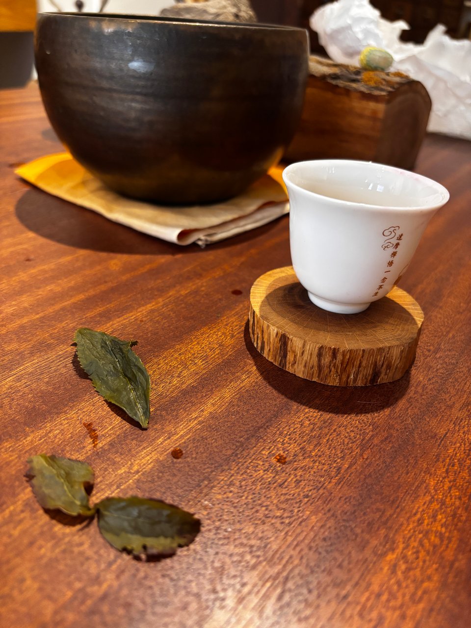Rehydrated tea leaves on a wooden table with white teacup and pot of tea at In Pursuit of Tea, New York City
