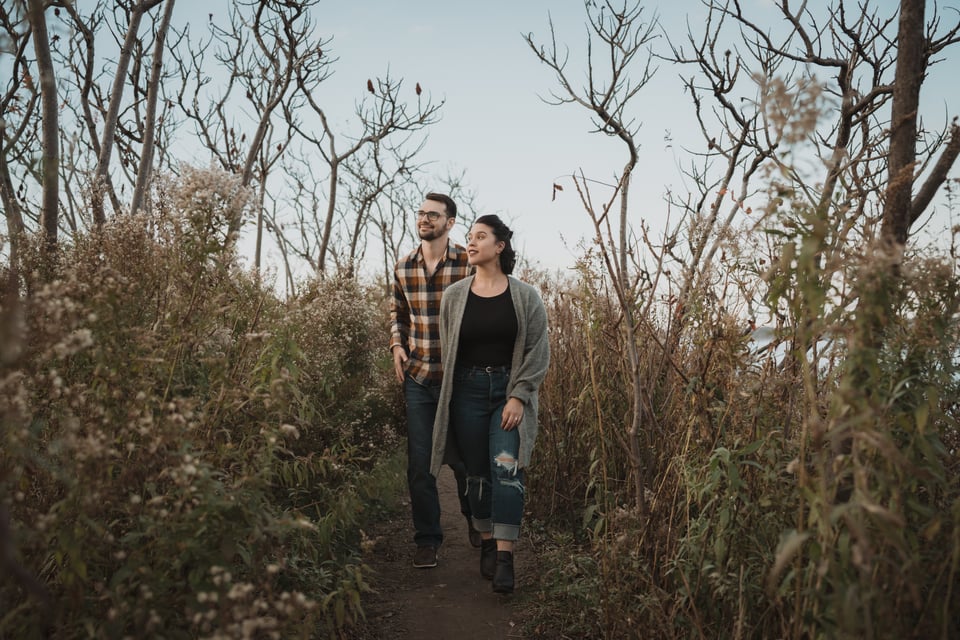 a couple walking through tall grasses