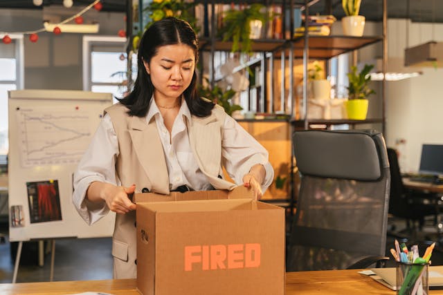 Woman in her office packing a box with the word fired on it.