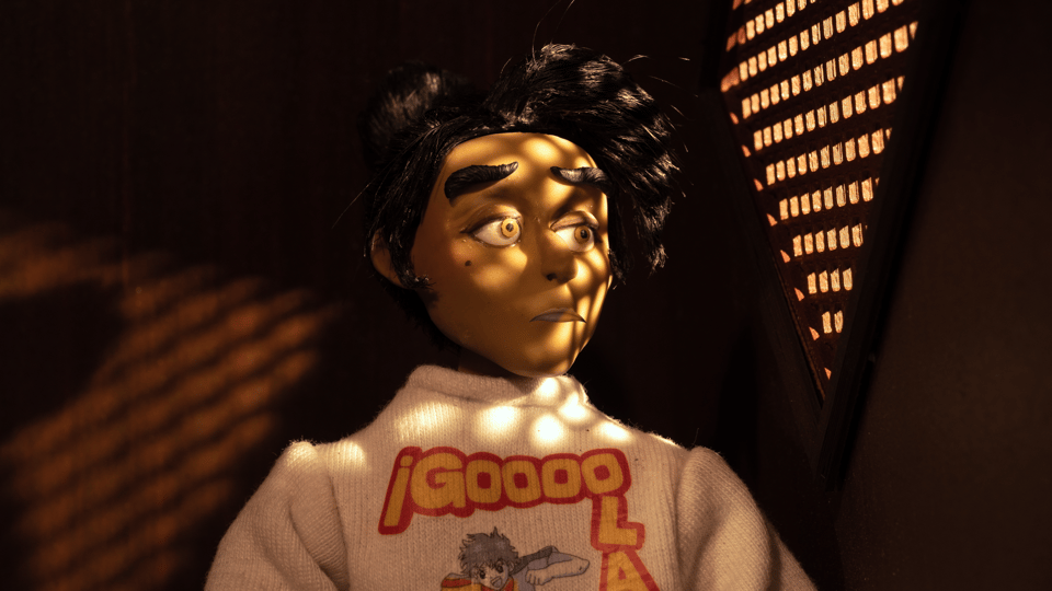A woman sits in a confession booth, notably wearing a Captain Tsubasa sweater