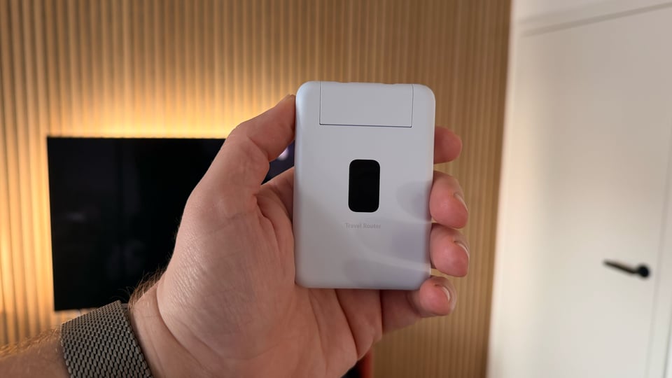 Ein Unifi Travel Router in meiner Hand füllt etwa die Handfläche aus.