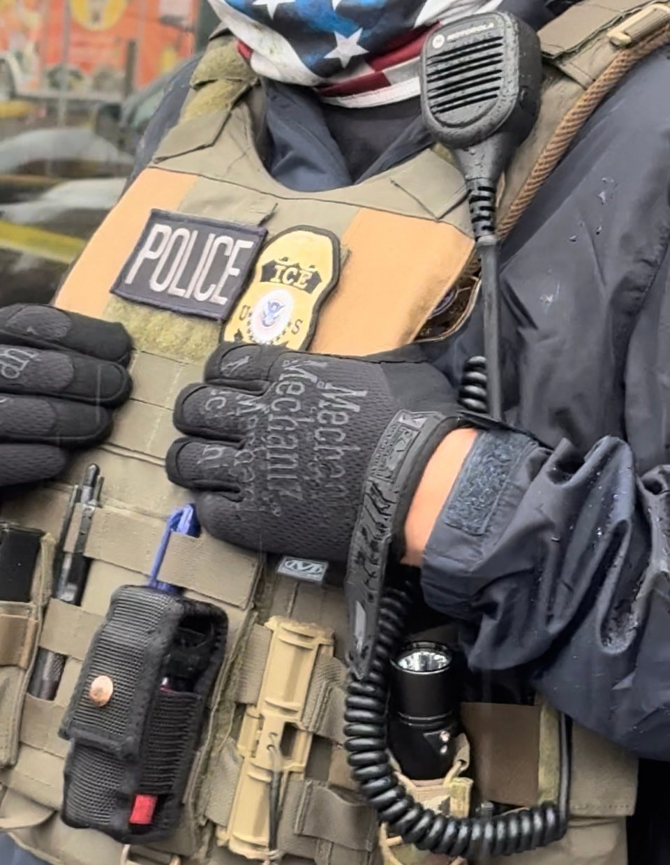 Faceless photo of ICE agent with identifying ICE patch on vest and American flag bandanna on the scene at Minneapolis ICE raid on June 2, 2025.