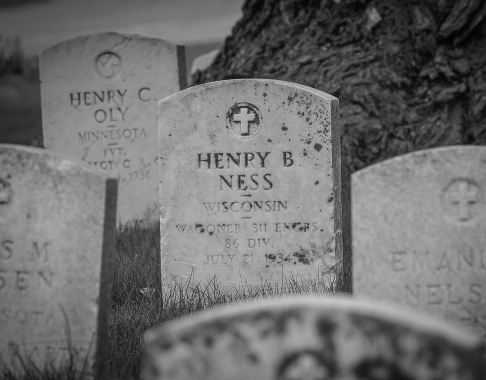 Headstone of Henry B. Ness amid other headstones in Crystal Lake Cemetery