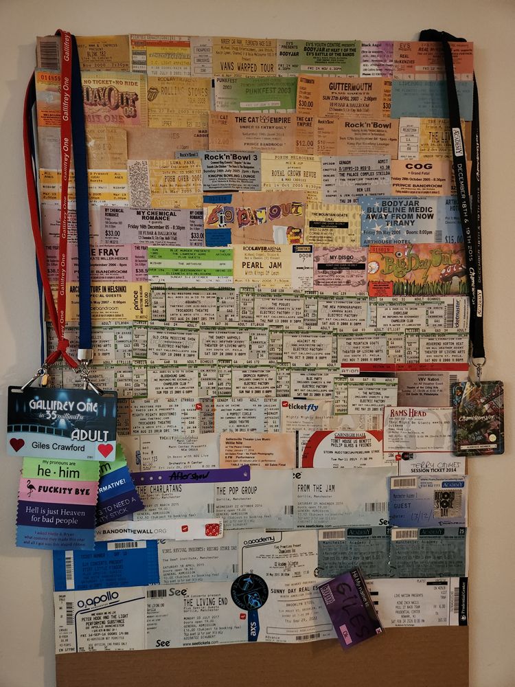 A board with hundreds of concert tickets stuck to it.