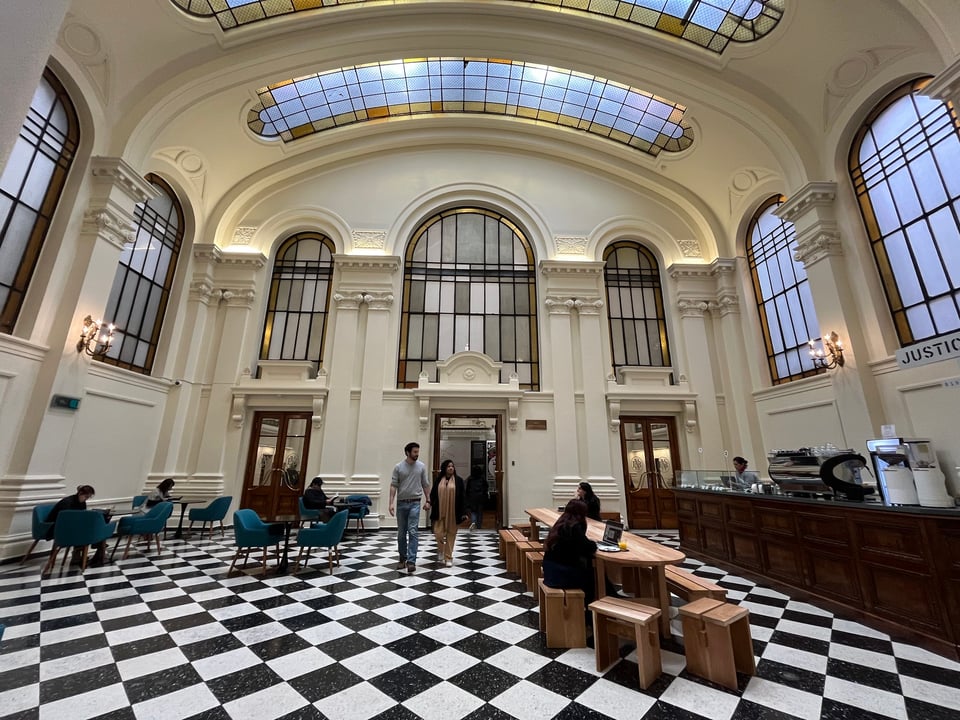 A room designed in the Beaux Arts style features a small coffee stand and checkered floors