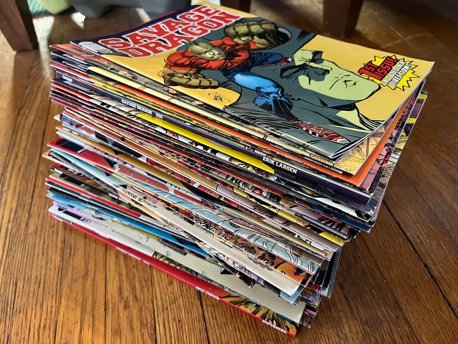 A tall stack of Savage Dragon comics on a hardwood floor