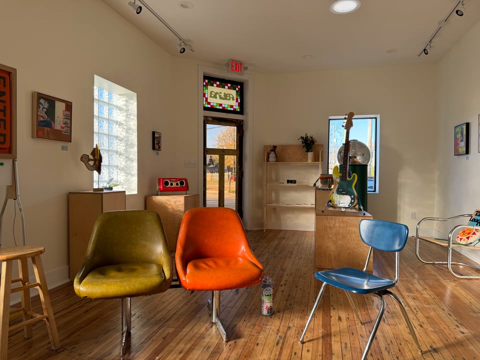 a picture of the interior of Patina Art Gallery after the podcast recording. It shows 3 chairs the podcast crew sat in surrounded by a large open room filled with art from a recent gallery.