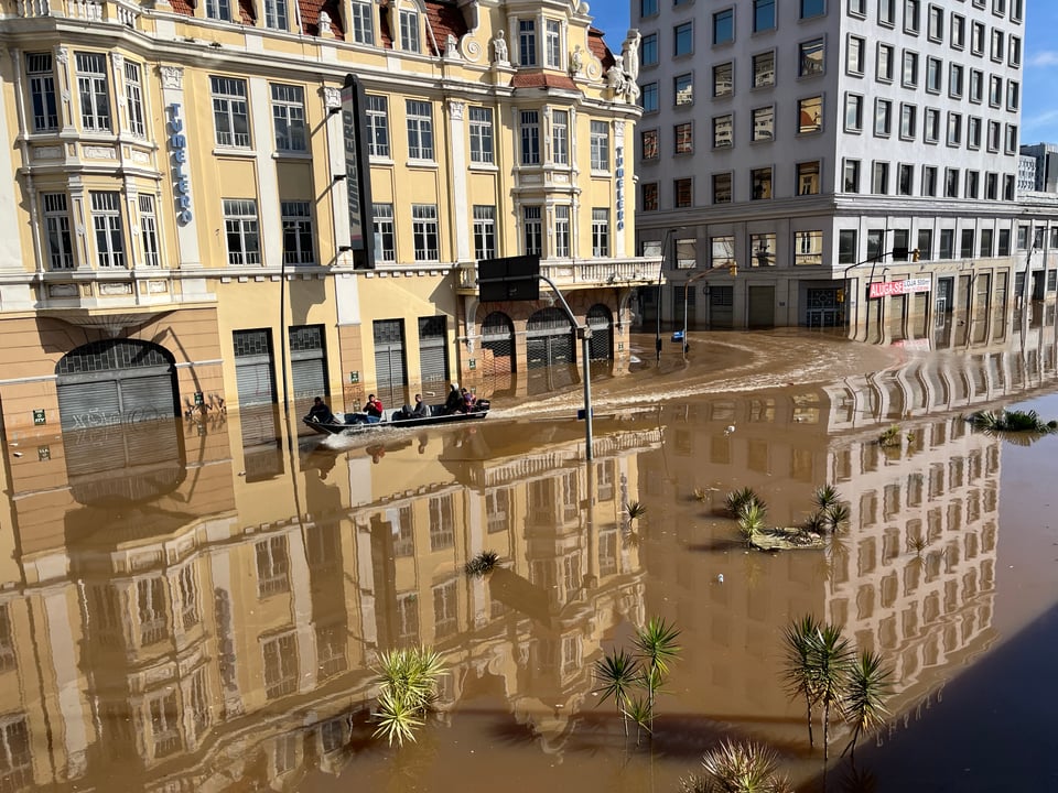 Um barco navega no centro alagado de Porto Alegre, em frente ao prédio do Tumelero.