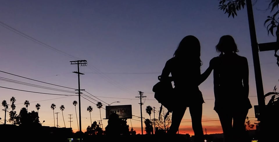 Still from the film TANGERINE, a silhouette of two trans women against an urban LA sunset