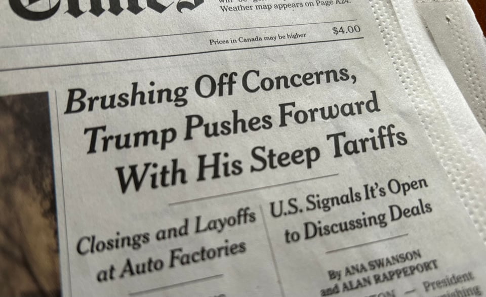 Photo of newspaper headline: "Brushing Off Concerns, Trump Pushes Forward With His Steep Tariffs," with sub-hed: "Closings and Layoffs of Auto Factories."