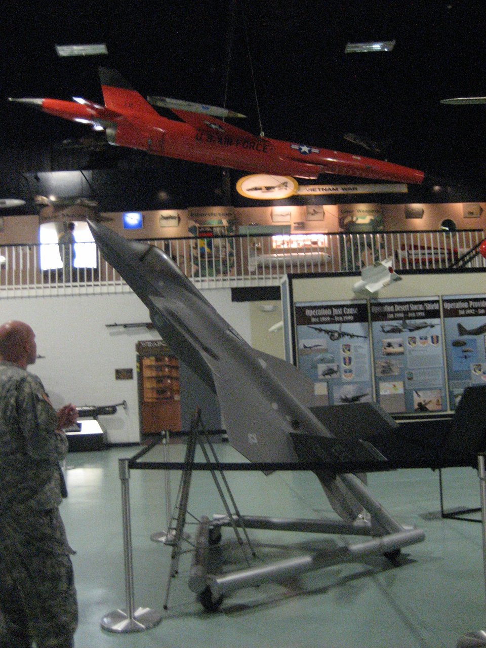 A hanger room containing a grey missile pointing upwards and a red one hanging from the ceiling.