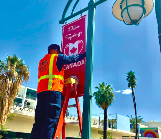 A city worker in downtown Palm Springs erects one of the banners festooned along the main drag proclaiming the city’s love for Canadians.