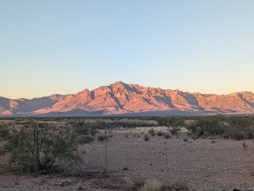 A craggy and striped mountain range stained gold and pink by sunset.