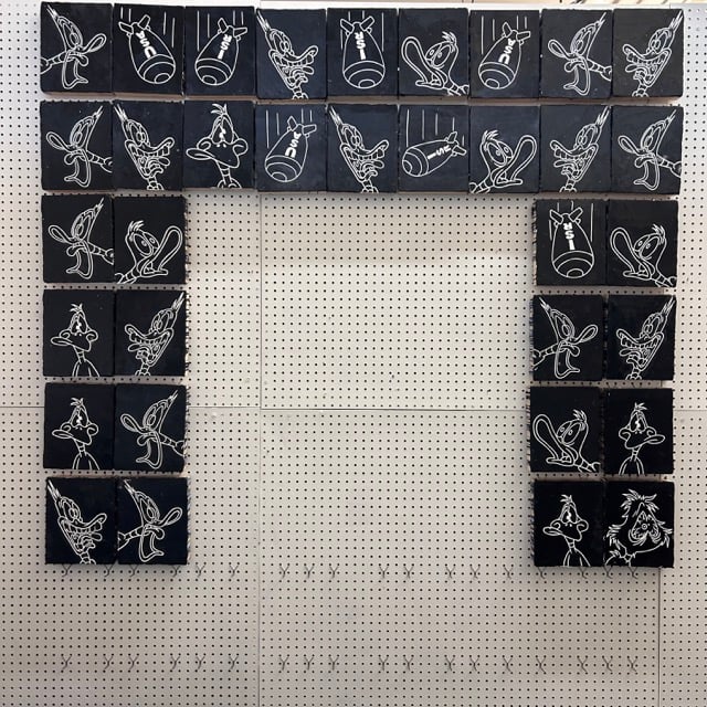 Several little black paintings of screaming ducks and falling bombs arranged in a frame with a hole in the center. For now.