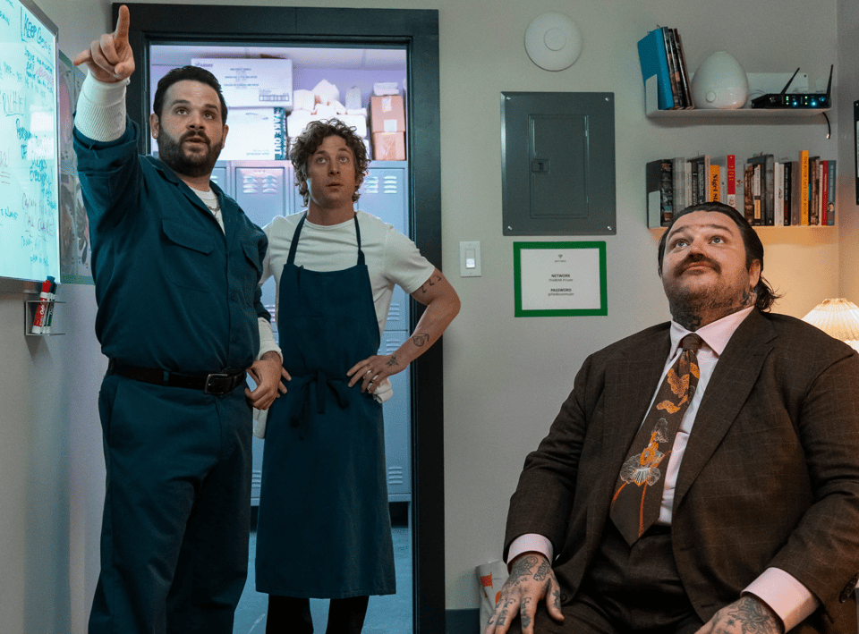 Three actors from the TV show The Bear, sitting in an office, looking at something off camera
