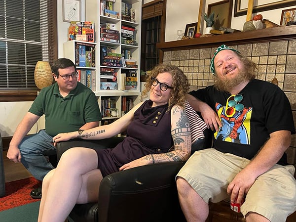 Alice sitting in a chair in our living room, our friends Carter and Doug on either side